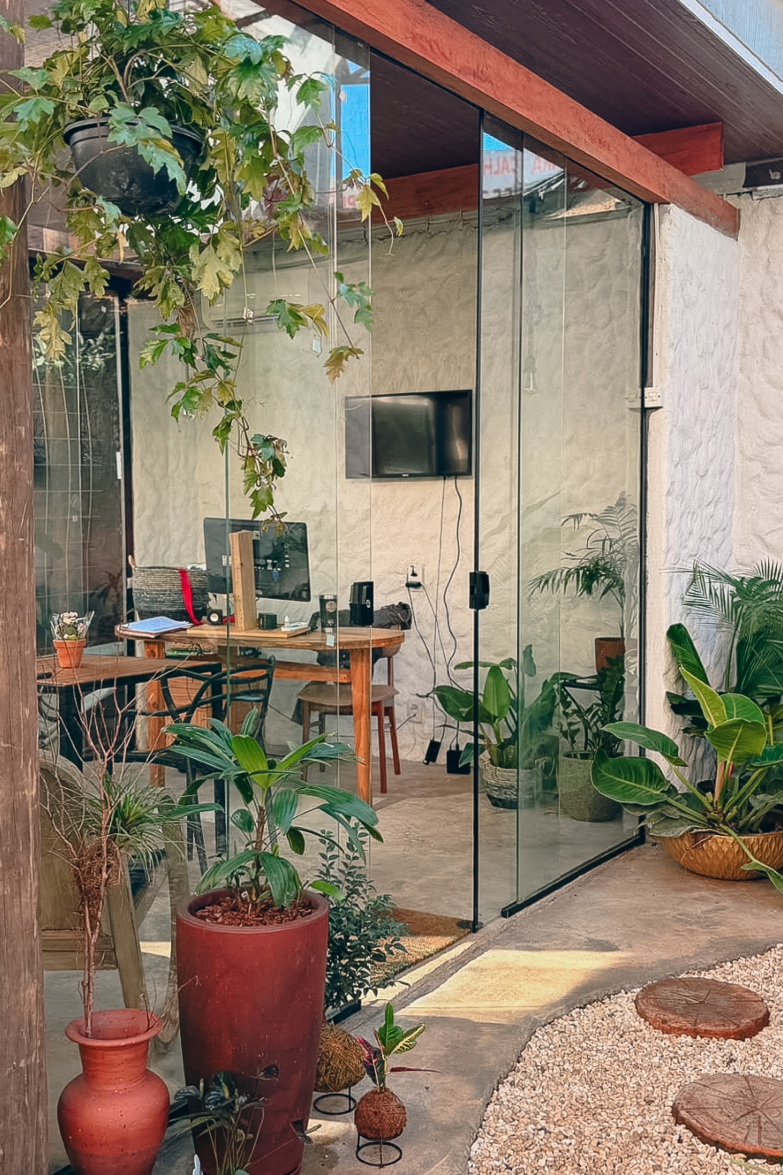 Coworking ArqVerdi com espaço de trabalho, madeira, vidro e vegetação.